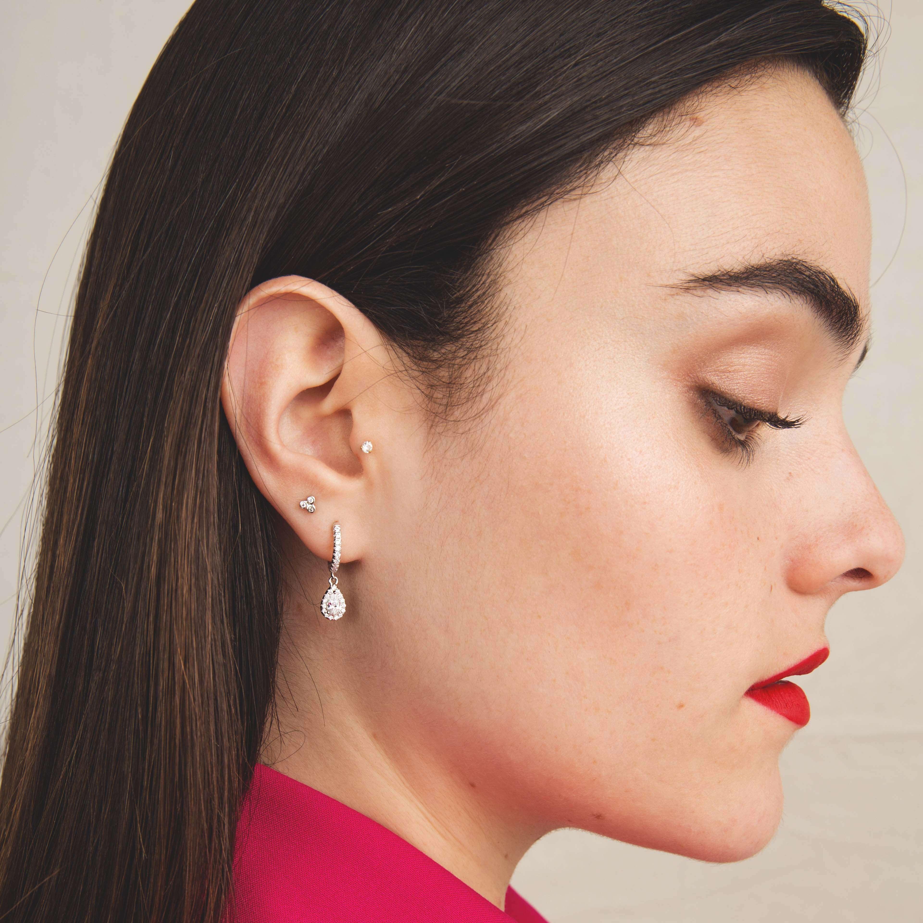 Boucle d’oreille brillante portée par une femme en veste rose