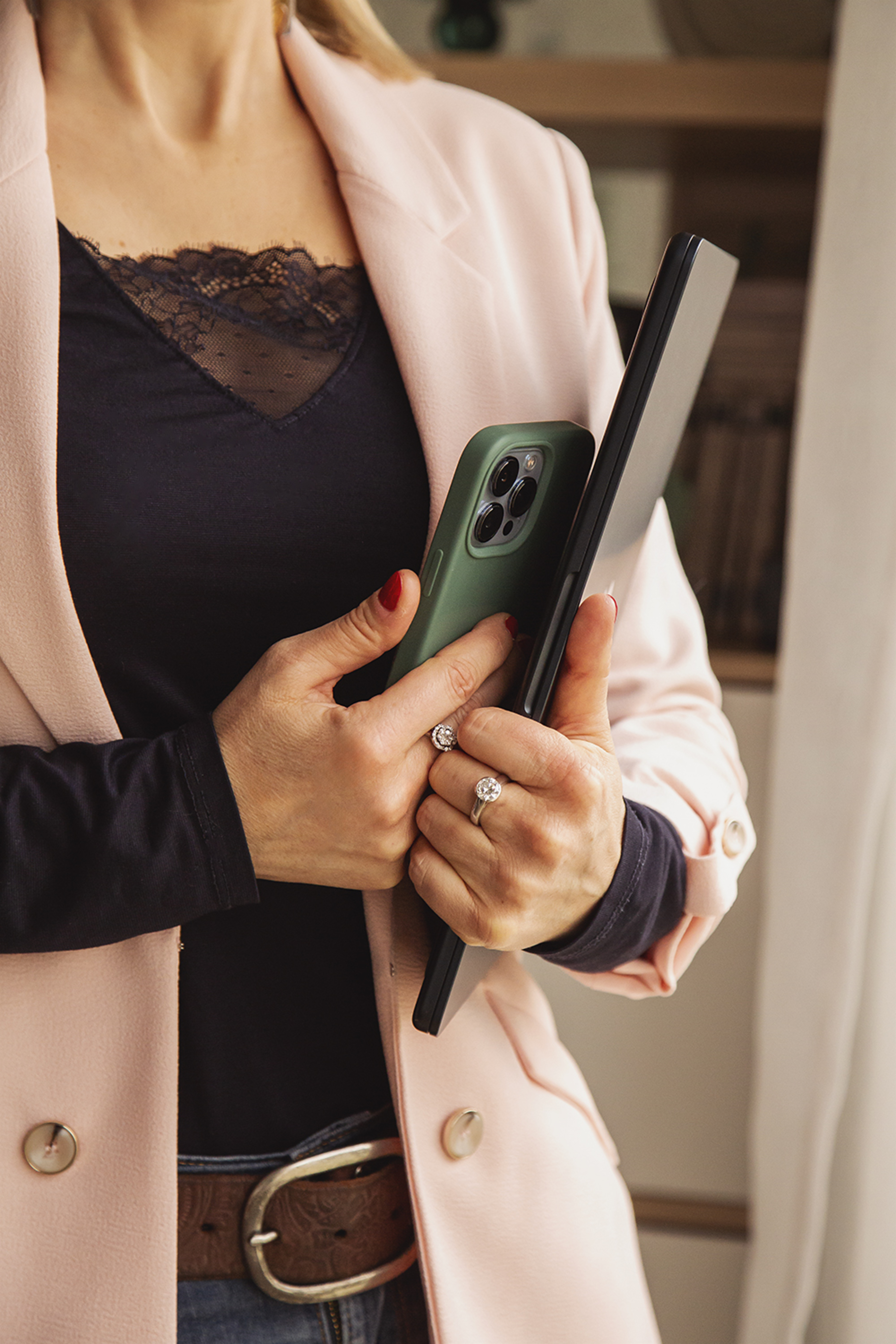thérapeute debout dans son cabinet tenant son téléphone et sa tablette dans les mains