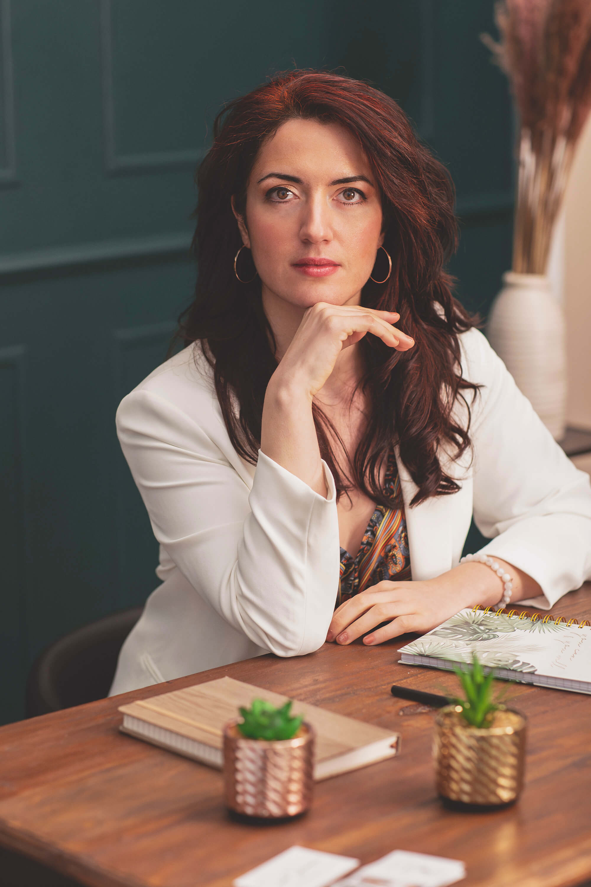 Portrait professionnel d’une femme brune posant avec assurance à son bureau