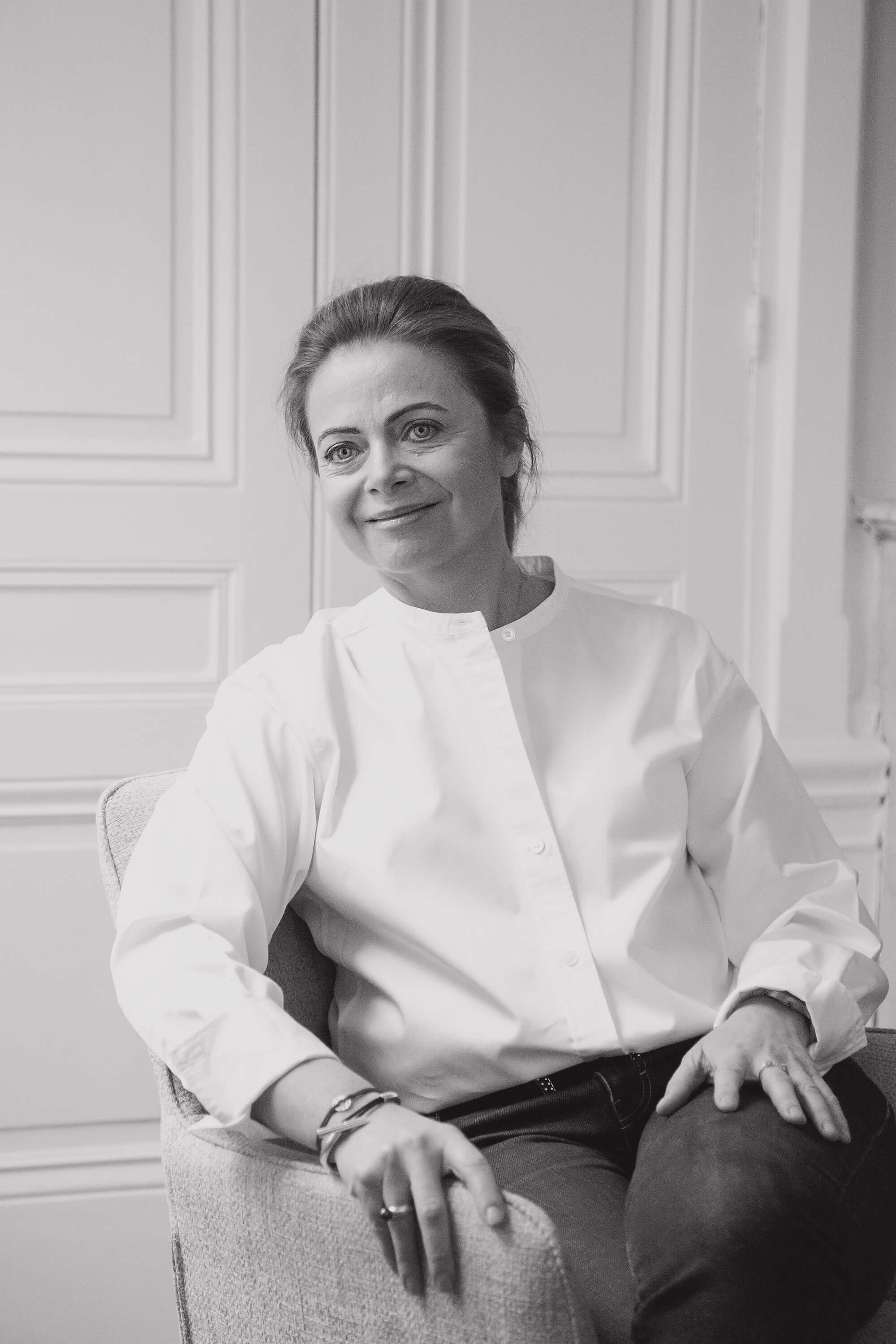 Portrait en noir et blanc d’une femme souriante assise sur un fauteuil dans bureau