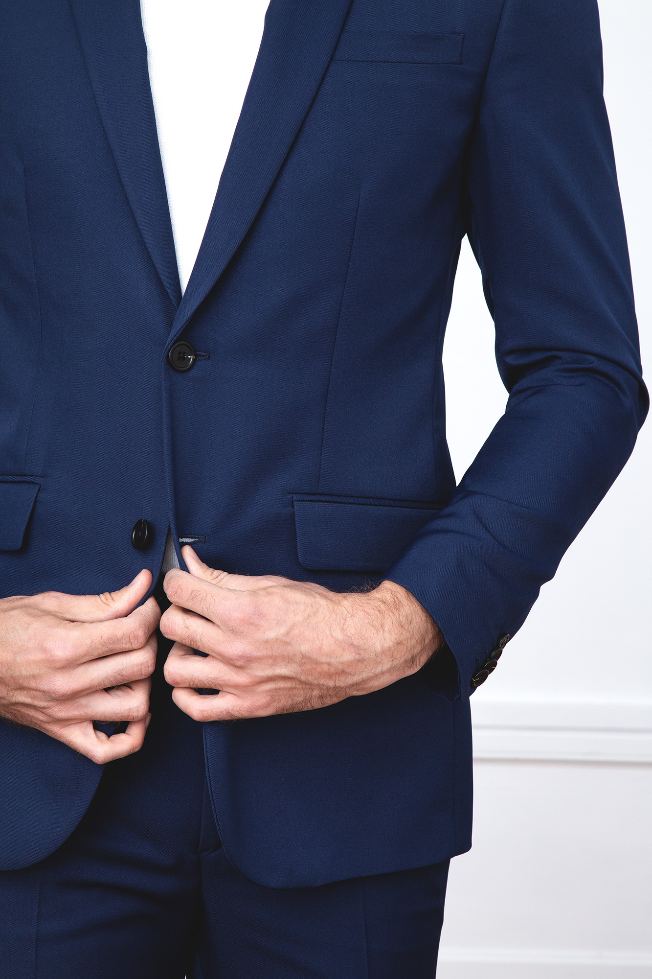 Homme en costume bleu marine ajustant sa veste, plan rapproché sur les mains