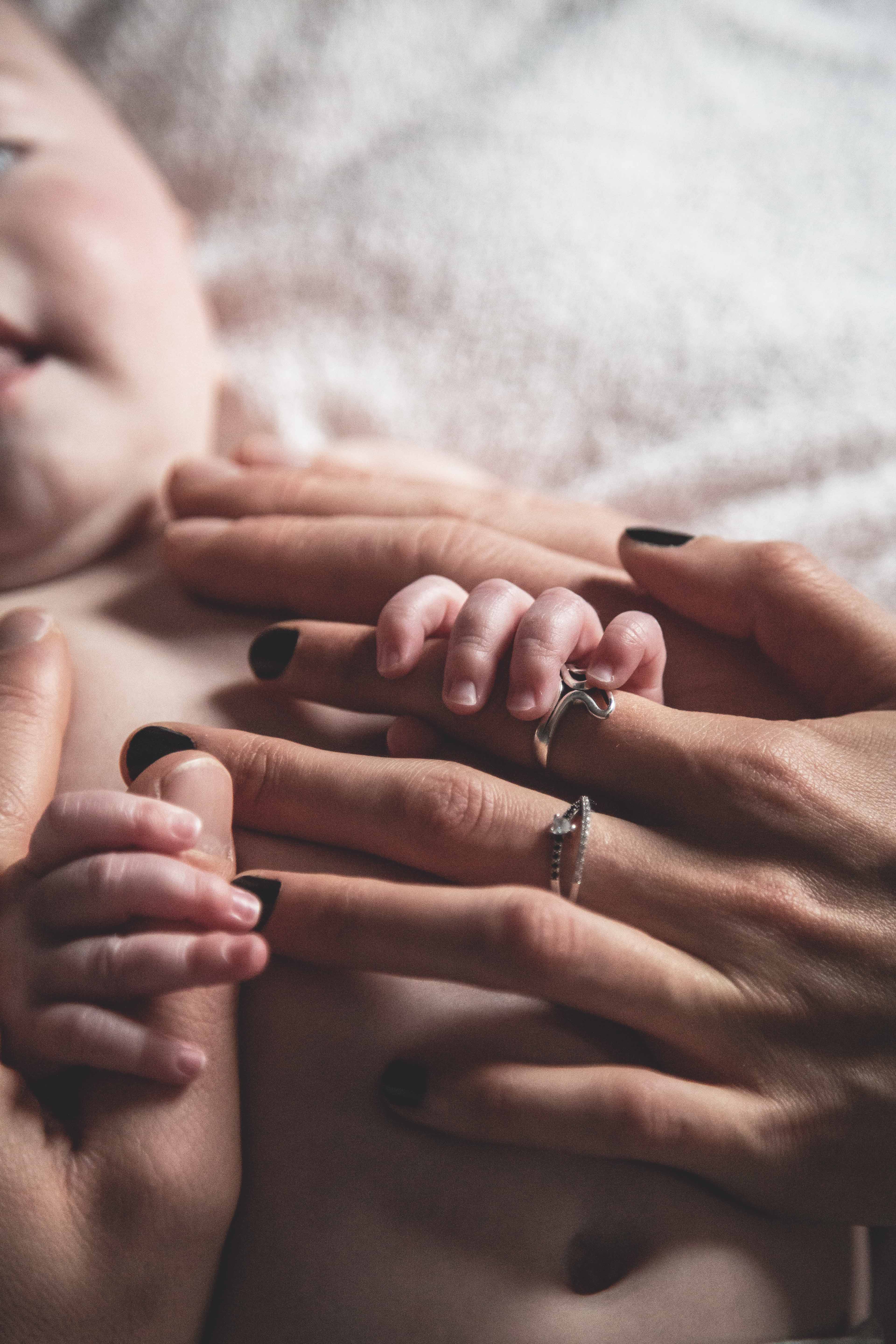 Main d’un bébé tenant les doigts de ses parents