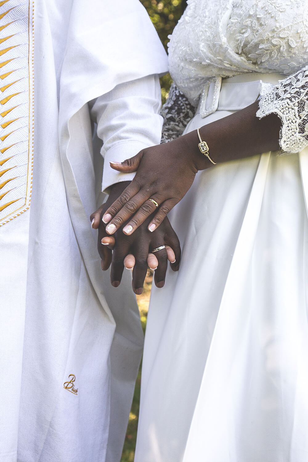 Main de la mariée posée sur celle du marié avec alliance en évidence